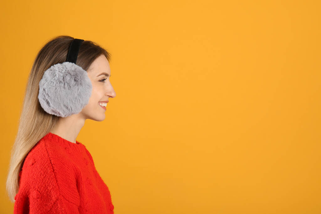 Щаслива жінка в теплих вухах на жовтому тлі, простір для тексту
 - Фото, зображення