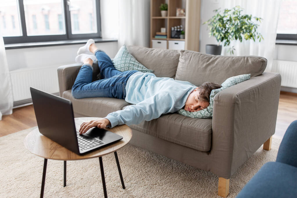 unatkozik férfi laptoppal heverő kanapén otthon - Fotó, kép