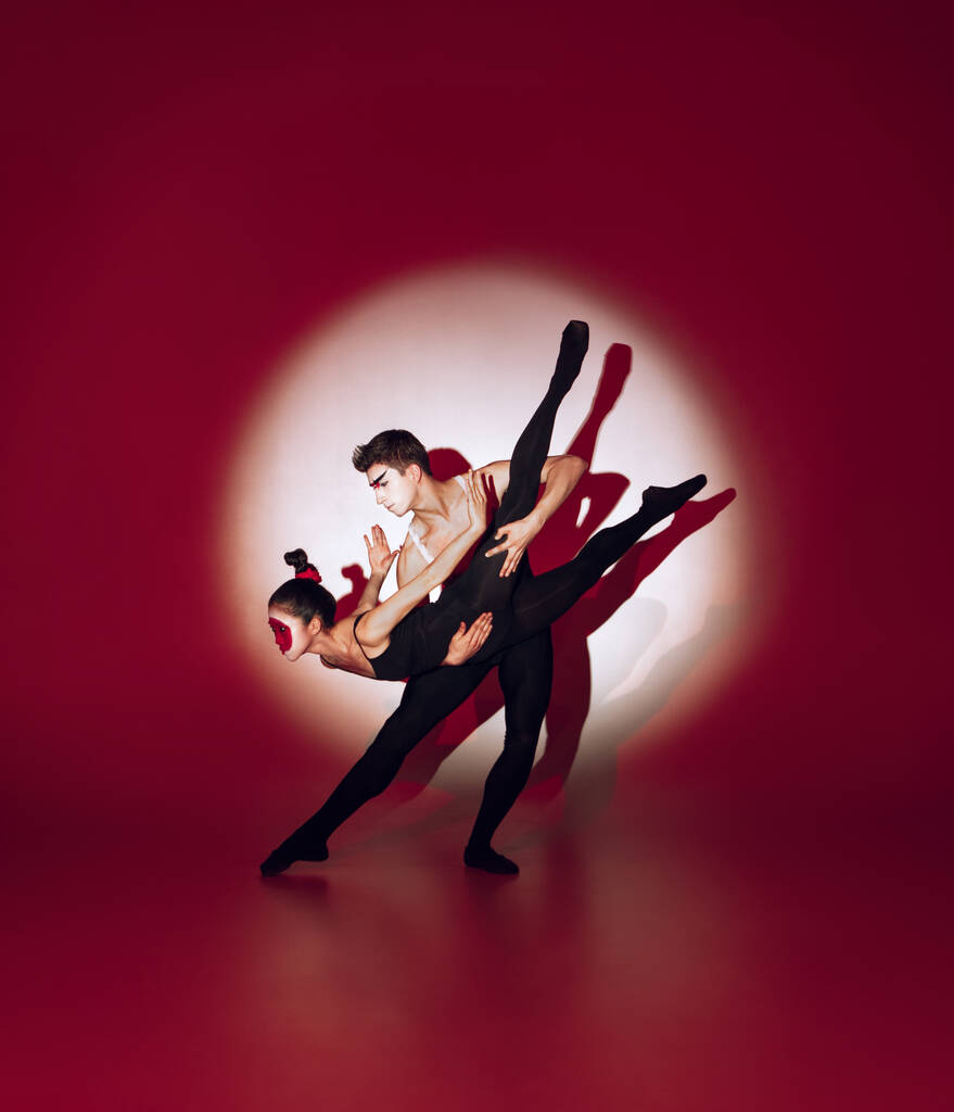 Bailarines de ballet bailando sobre fondo rojo del estudio. Diseño moderno. Luz conceptual colorida contemporánea como sol naciente en Japón. - Foto, imagen