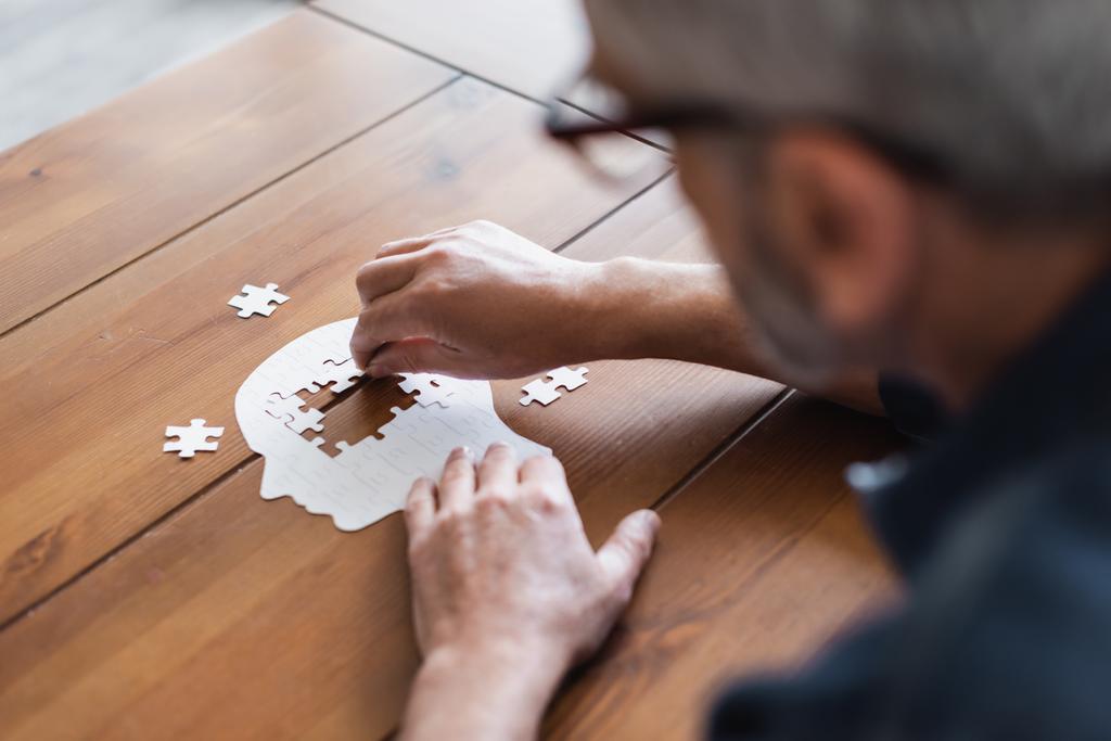 Zamazany mężczyzna z demencją składane układanki na stole w domu  - Zdjęcie, obraz