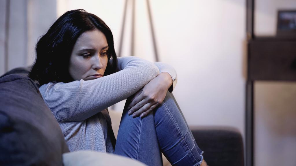 depresivní žena sedí na pohovce v self-objetí pózovat doma - Fotografie, Obrázek