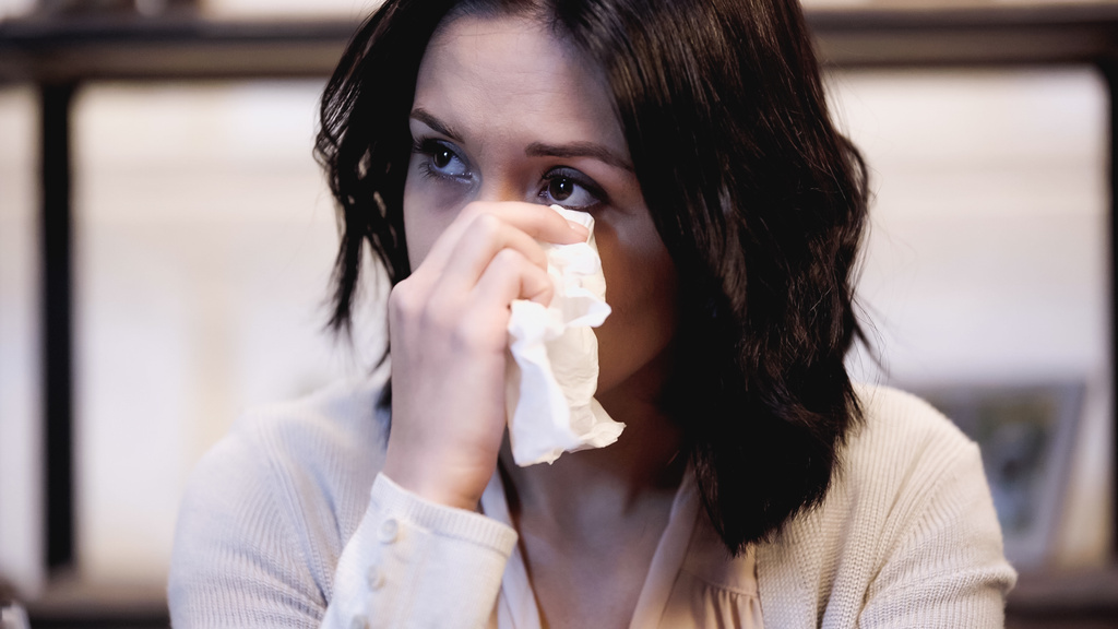 μελαχρινή γυναίκα που σκουπίζει δάκρυα με χαρτοπετσέτα στο σπίτι - Φωτογραφία, εικόνα
