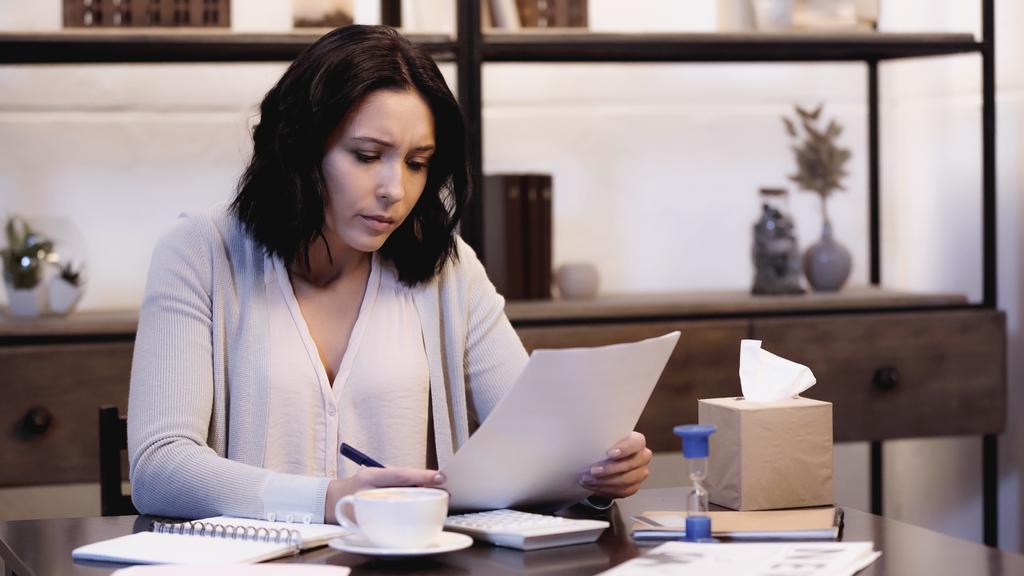 депресивна жінка сидить на столі і дивиться через документи вдома
 - Фото, зображення