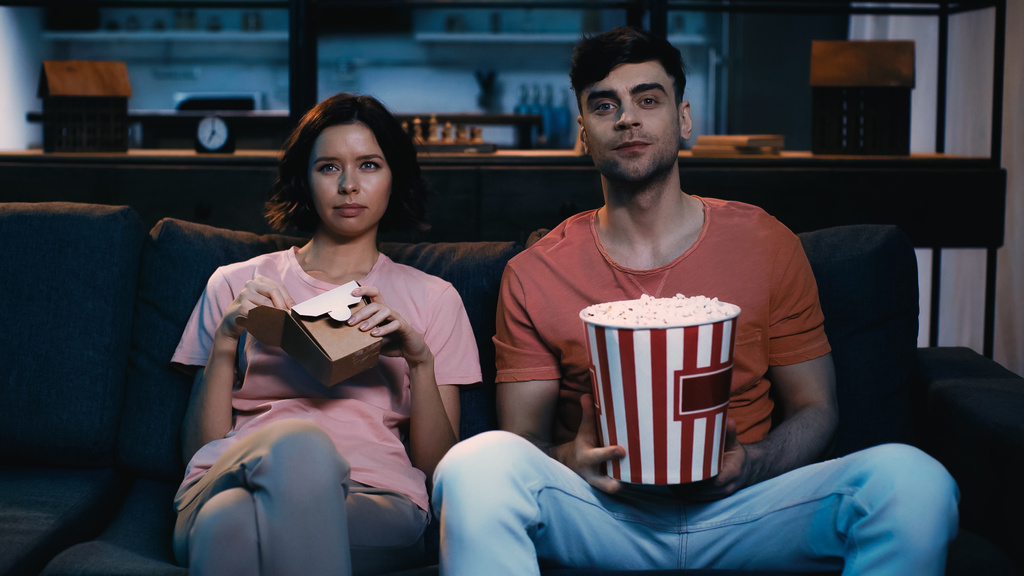 mies tilalla ämpäri popcornia ja katsella elokuvan tyttöystävä tilalla pahvilaatikko kiinalaista ruokaa  - Valokuva, kuva