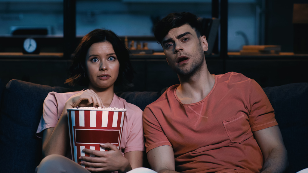 verrast vrouw met popcorn emmer en kijken naar film met vriendje  - Foto, afbeelding