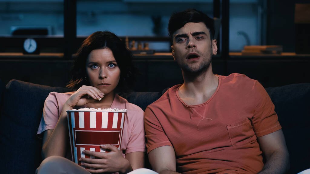 brunetta donna tenendo popcorn secchio e guardando film con fidanzato  - Foto, immagini
