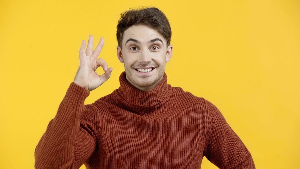 Sorrindo homem em suéter mostrando gesto ok isolado em amarelo  - Foto, Imagem