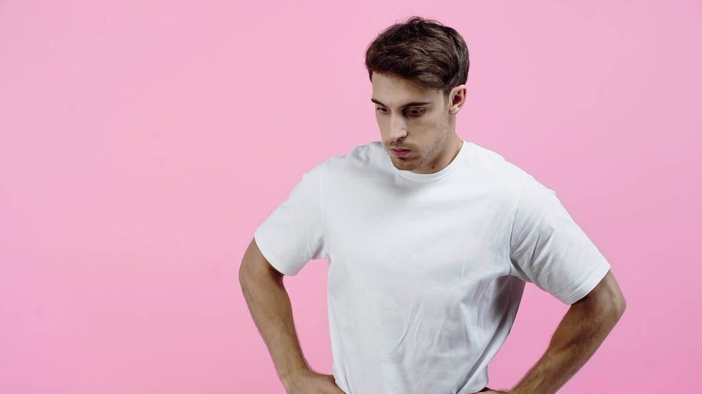 Удумливий чоловік у білій футболці стоїть ізольовано на рожевому
 - Фото, зображення