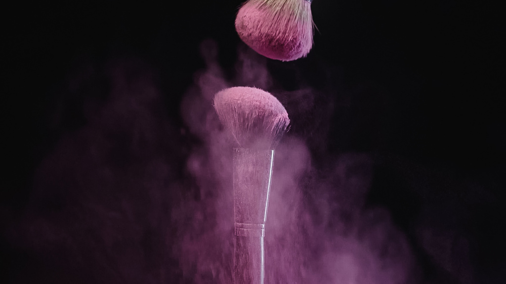 απαλά πινέλα καλλυντικών κοντά σε πιτσιλιές ροζ σκόνης σε μαύρο φόντο - Φωτογραφία, εικόνα