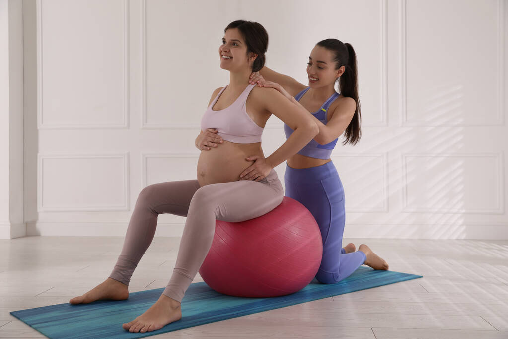 Εκπαιδευτής που δουλεύει με έγκυο γυναίκα στο γυμναστήριο. Προετοιμασία για τη γέννηση του παιδιού - Φωτογραφία, εικόνα
