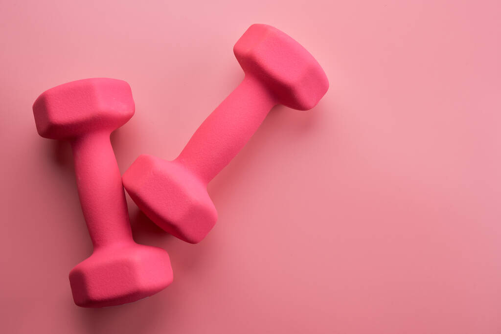 Dos pesas femeninas de color rosa aisladas sobre fondo rosa de cerca con espacio para copiar. Concepto de fitness, pérdida de peso y actividad deportiva, vista superior, cama plana - Foto, imagen