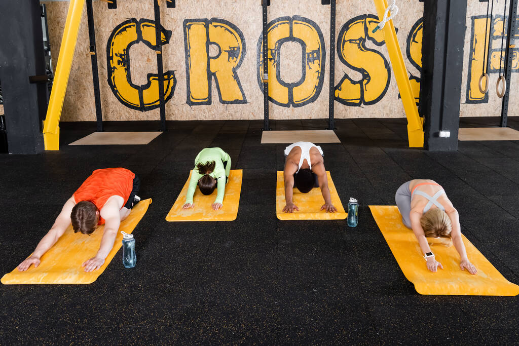 Тренировка спортивной группы в сидячей позе сгиба вперед на фитнес-ковриках - Фото, изображение
