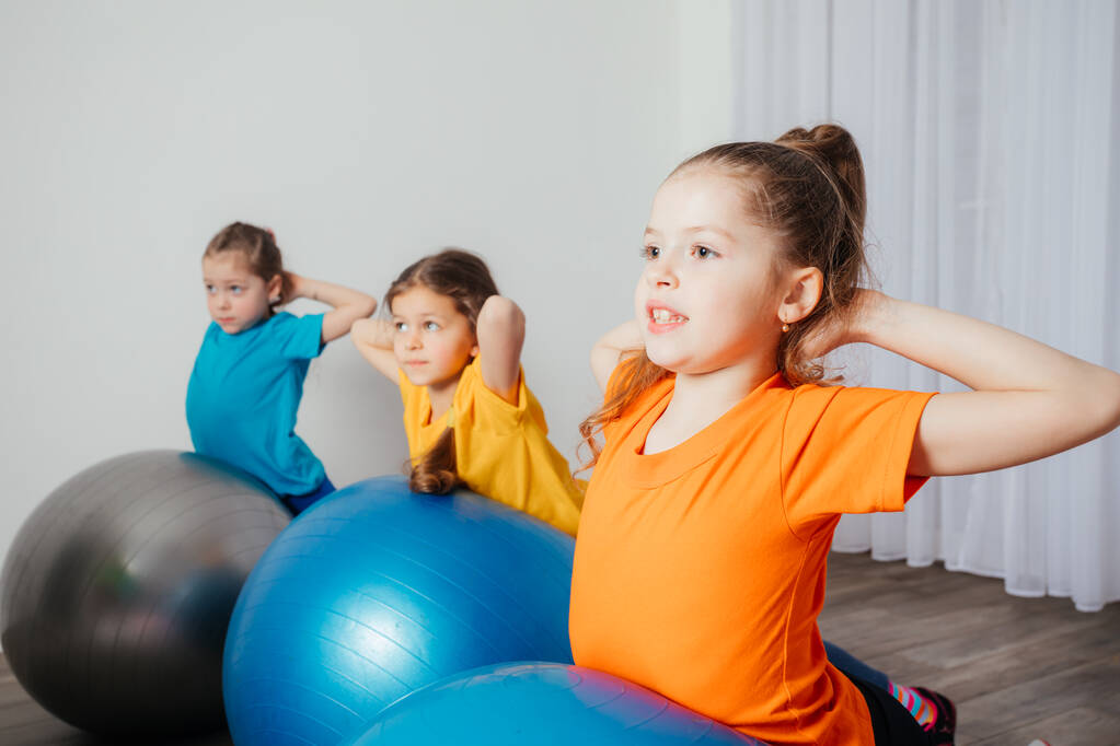 Niños haciendo ejercicios físicos en grandes bolas de fitball - Foto, Imagen