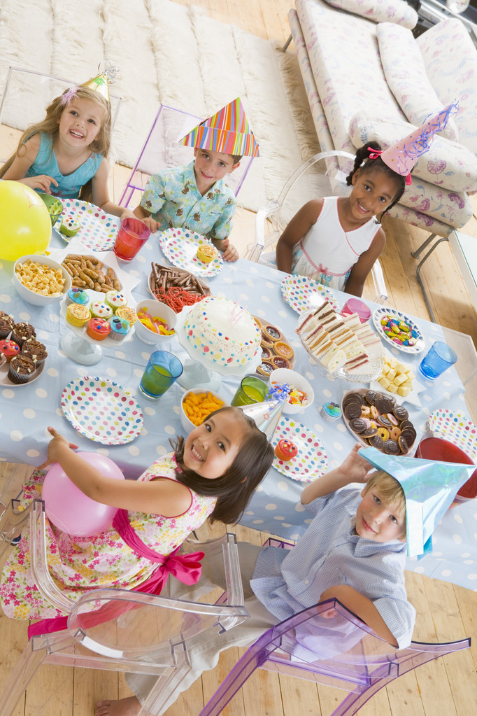 Crianças pequenas na festa sentadas à mesa com comida sorrindo
 - Foto, Imagem