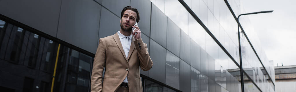 бізнесмен розмовляє на мобільному телефоні біля будівлі, банер
 - Фото, зображення