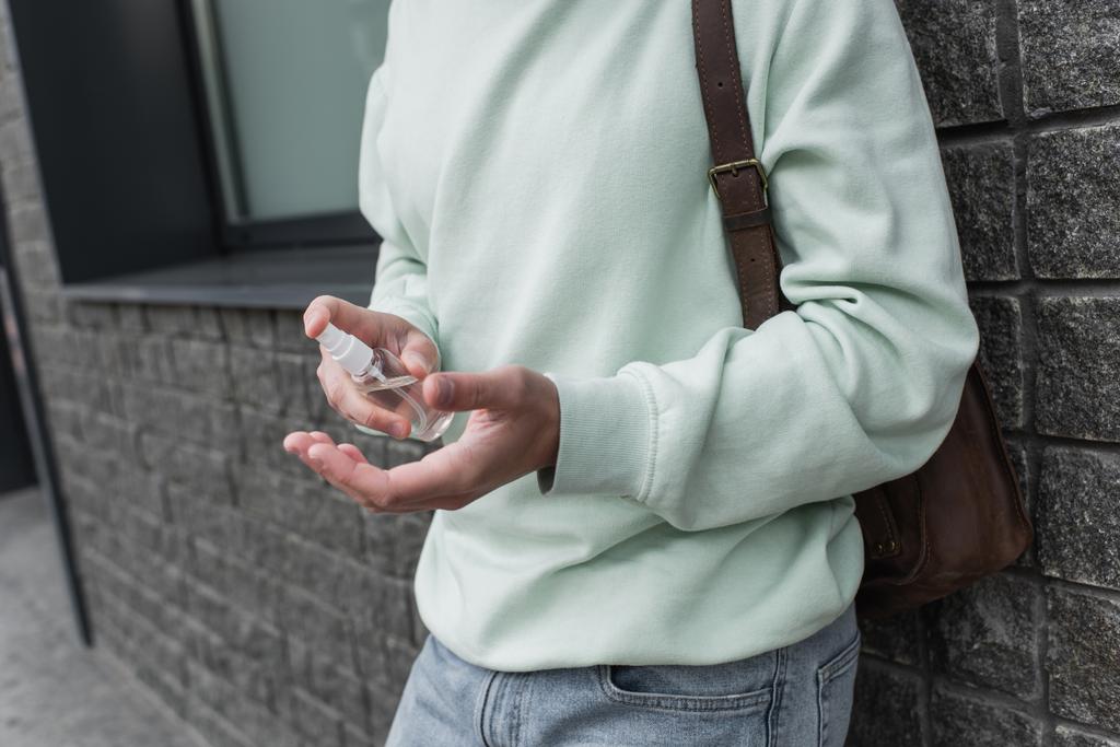 rajattu näkymä nuori mies soveltamalla sanitizer käsillä - Valokuva, kuva