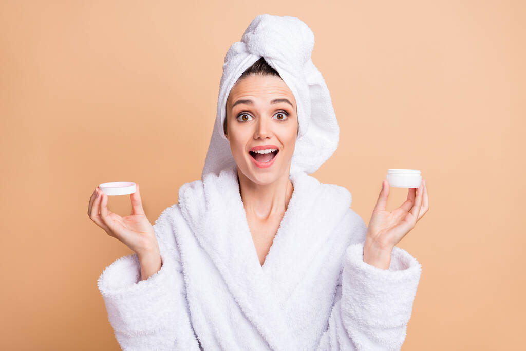 Foto di stupito felice donna affascinante tenere crema trattamento scioccato isolato su sfondo di colore beige - Foto, immagini