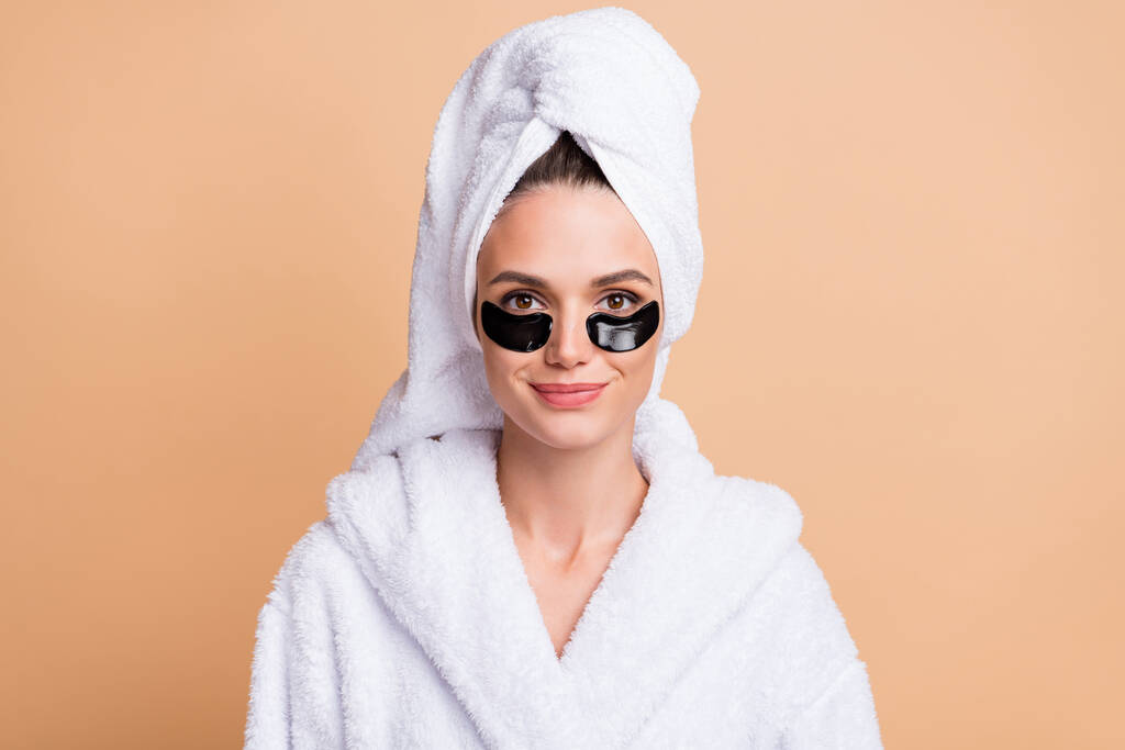 Foto van charmante jonge vrouw dragen ooglapje cosmetica goed humeur geïsoleerd op beige kleur achtergrond - Foto, afbeelding