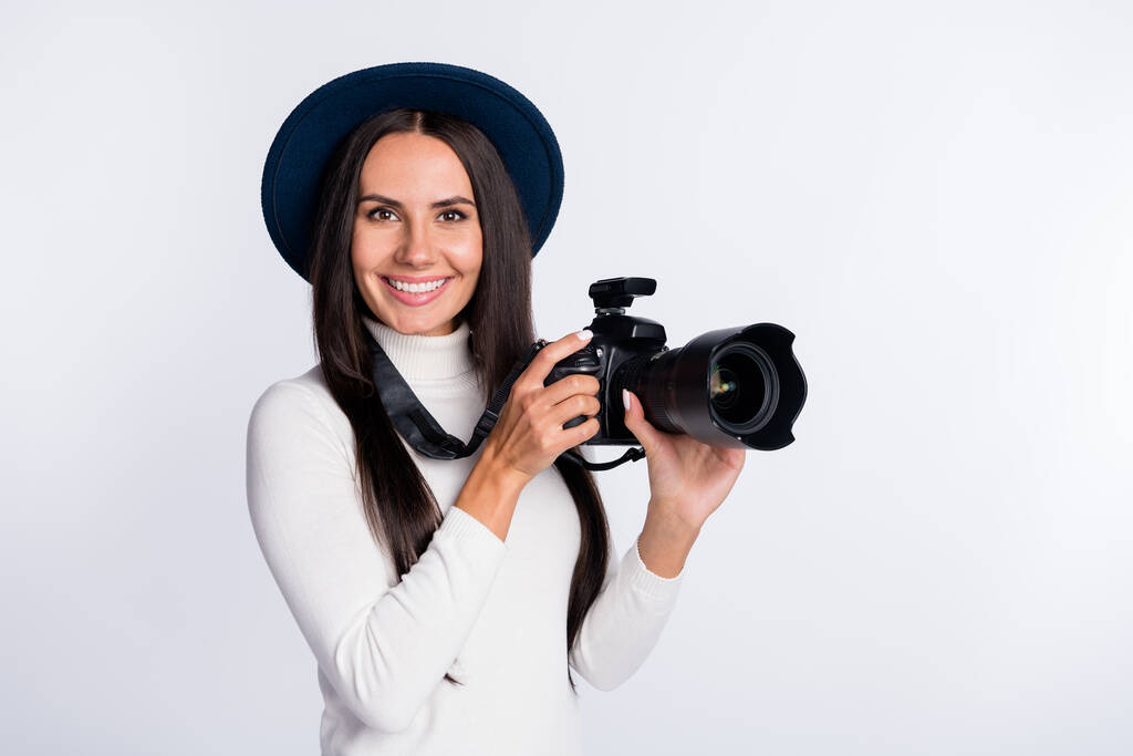 Photo d'attrayant photographe positif fille tenir la main caméra studio porter chapeau sourire isolé sur fond de couleur grise - Photo, image