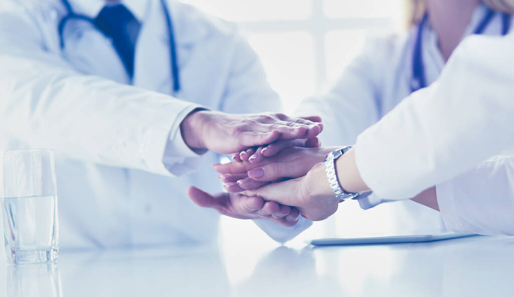 Een team van dokters die elkaars handen bij elkaar steken, close-up - Foto, afbeelding