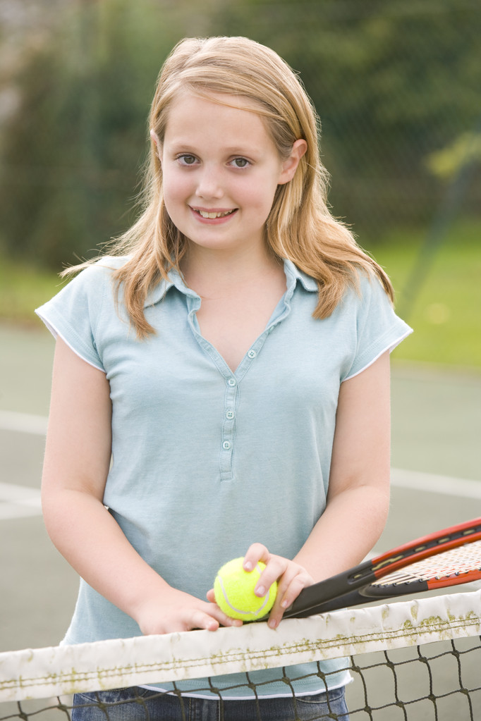 Young girl with racket on tennis court smiling - Photo, Image