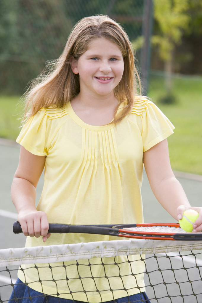 Young girl with racket on tennis court smiling - Photo, Image