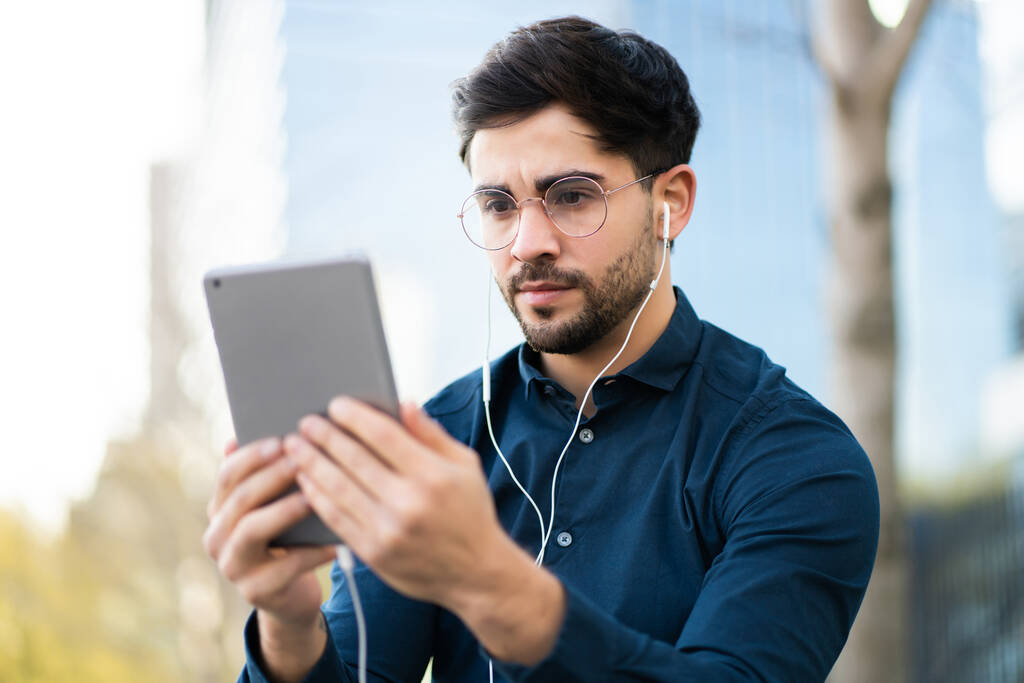 Junger Mann telefoniert mit digitalem Tablet im Freien. - Foto, Bild
