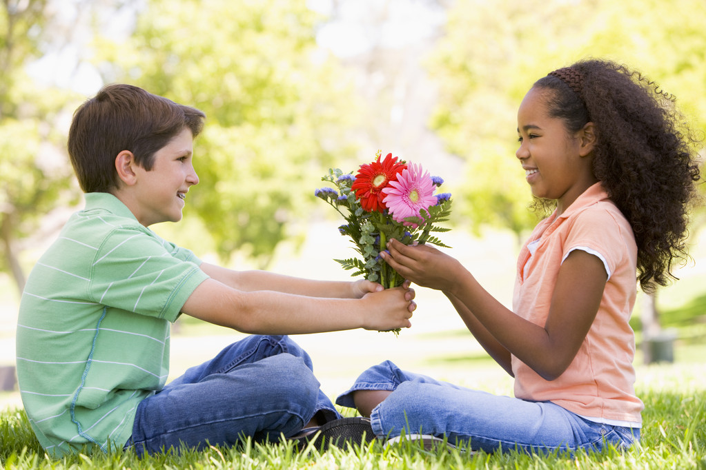 νεαρό αγόρι δίνοντας λουλούδια νεαρό κορίτσι και χαμογελαστός - Φωτογραφία, εικόνα