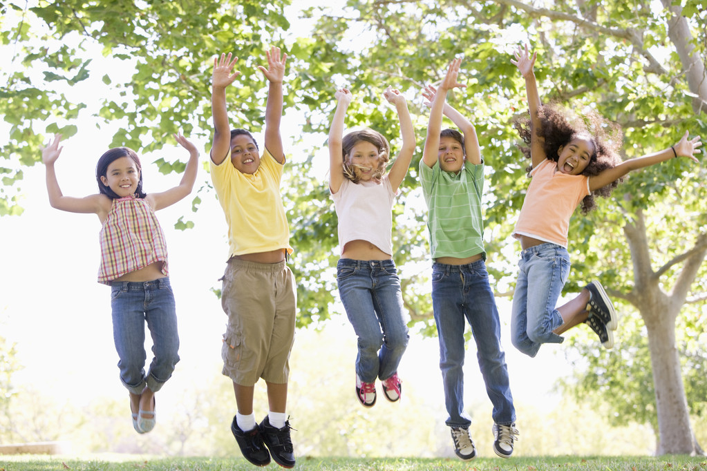 Viisi nuorta ystävää hyppii ulkona hymyillen
 - Valokuva, kuva