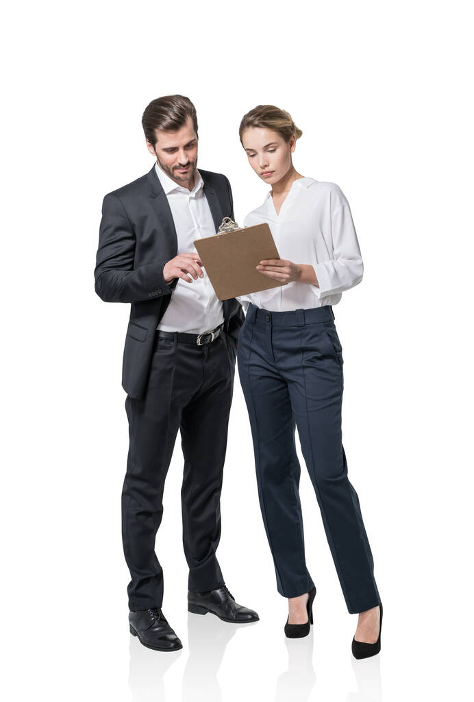 Full length of businesswoman and businessman in formal φοράει κατέχει και σκεπτική κοιτάζοντας στο πρόχειρο με χαρτιά ή σύμβαση. Επιχειρηματίες απομονωμένοι σε λευκό φόντο. Έννοια της ομαδικής εργασίας - Φωτογραφία, εικόνα