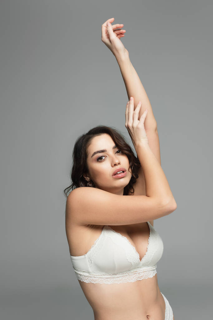 Kaunis nainen rintaliivit koskettaa kädet eristetty harmaa  - Valokuva, kuva