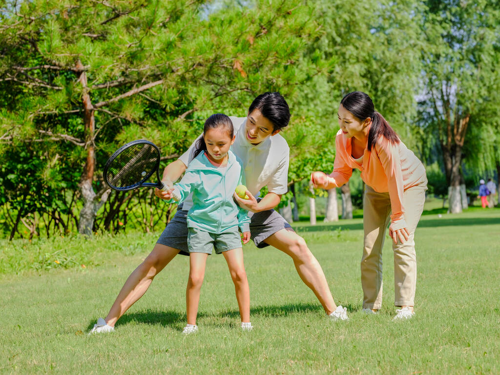 Счастливая семья из трех человек играет в теннис в парке - Фото, изображение