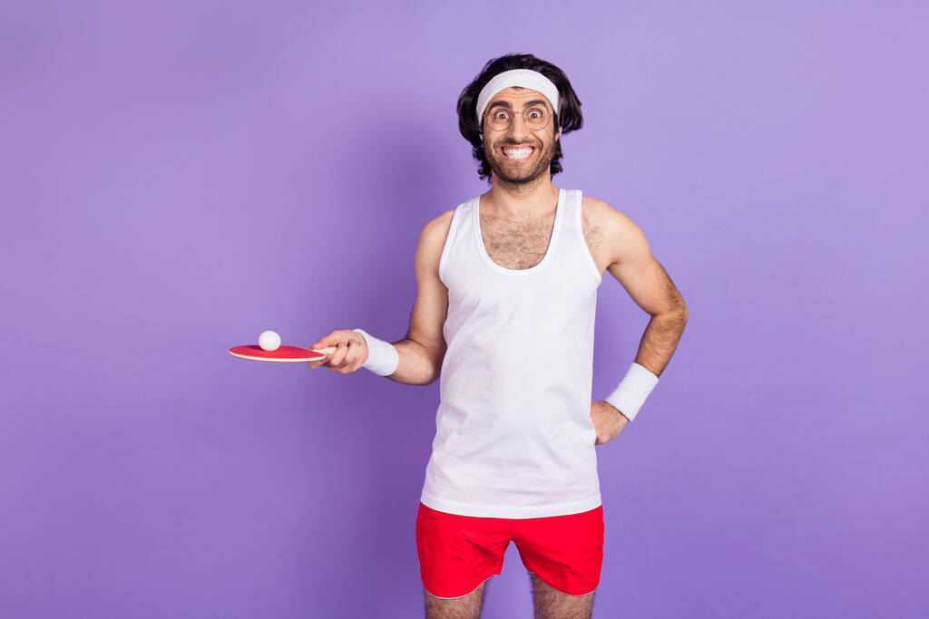Photo de fou heureux jeune homme funky tenir main ping pong raquette sourire isolé sur fond de couleur violette - Photo, image