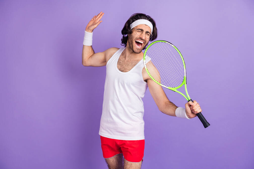 Photo of guy hold racket open mouth sing closed eyes wear headband sportswear glasses isolated purple background - Photo, Image