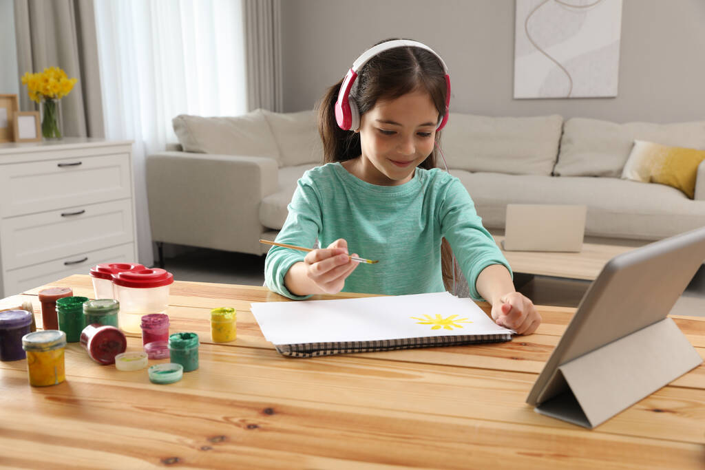 Menina com fones de ouvido desenhando em papel na aula on-line dentro de casa. Ensino à distância - Foto, Imagem