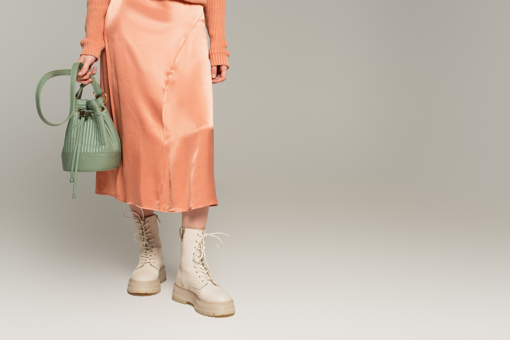 μερική άποψη της κομψής γυναίκας σε μεταξωτή φούστα κρατώντας τσάντα σε γκρι  - Φωτογραφία, εικόνα