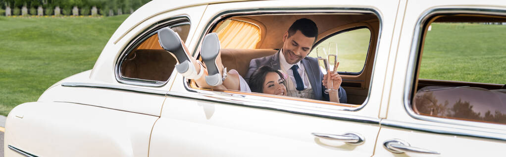 Recém-casados sorridentes segurando copos de champanhe no carro vintage, banner  - Foto, Imagem