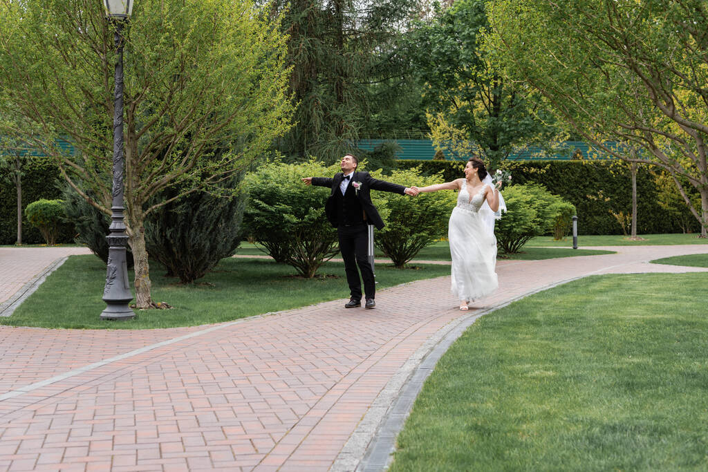 Boldog friss házasok, a parkban sétáló csokorral  - Fotó, kép