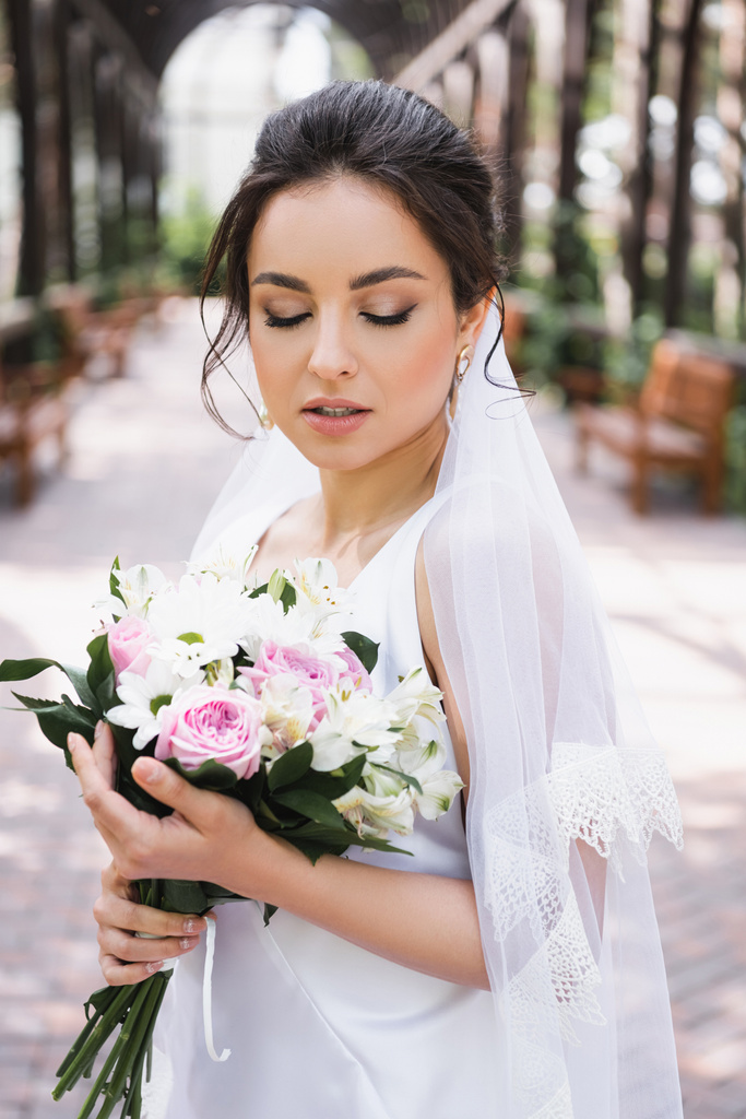 Mooie bruid houdt bruiloft boeket buiten  - Foto, afbeelding