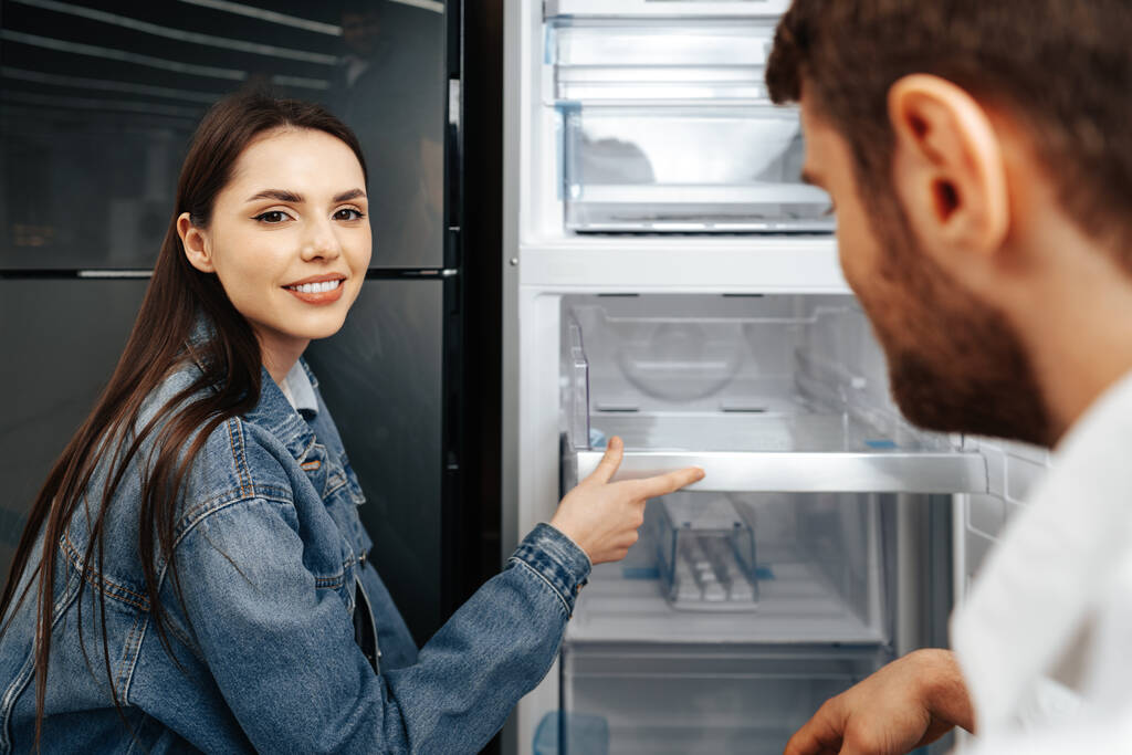 Молодая пара выбирает новый холодильник в магазине бытовой техники - Фото, изображение