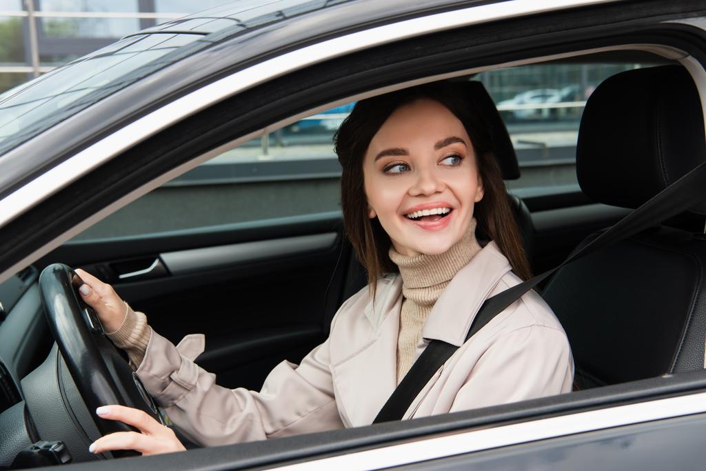 radosna młoda kobieta odwracając wzrok podczas jazdy samochodem - Zdjęcie, obraz
