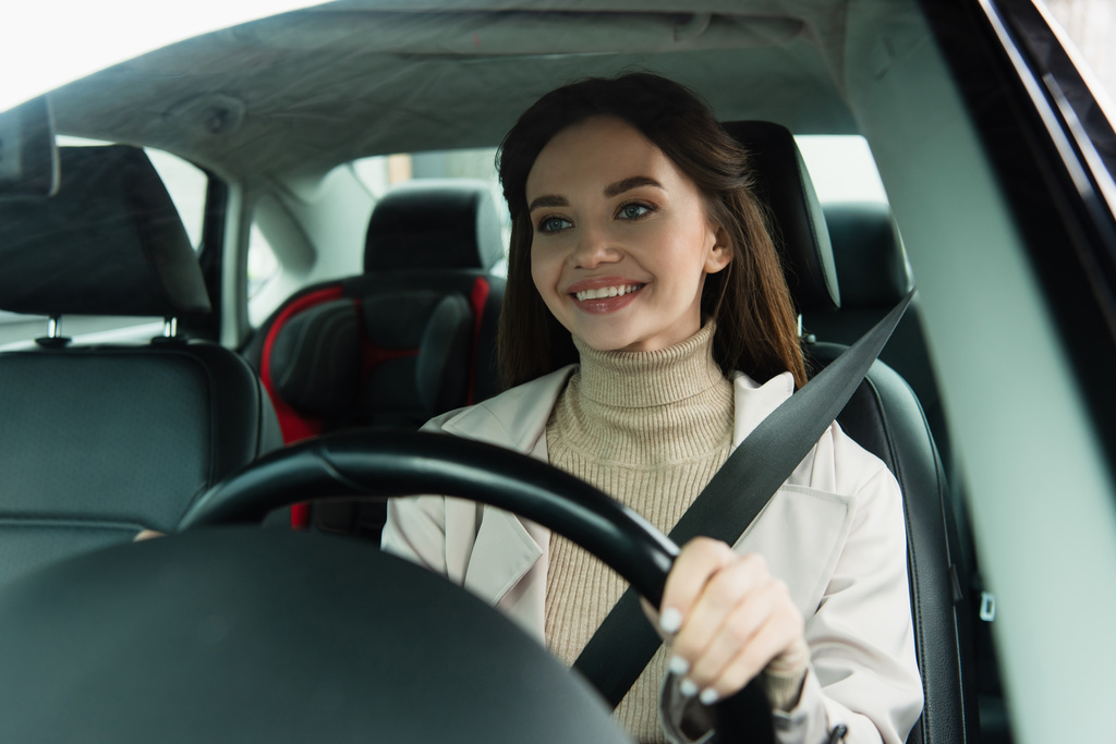 zadowolona kobieta jazdy samochodem w mieście na zamazanym pierwszym planie - Zdjęcie, obraz