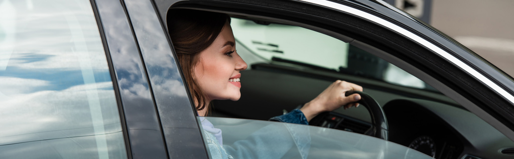iloinen nuori nainen ajaa autoa kaupungissa, banneri - Valokuva, kuva