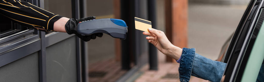 vista parziale del conducente con carta di credito vicino cassiere con terminale di pagamento, banner - Foto, immagini