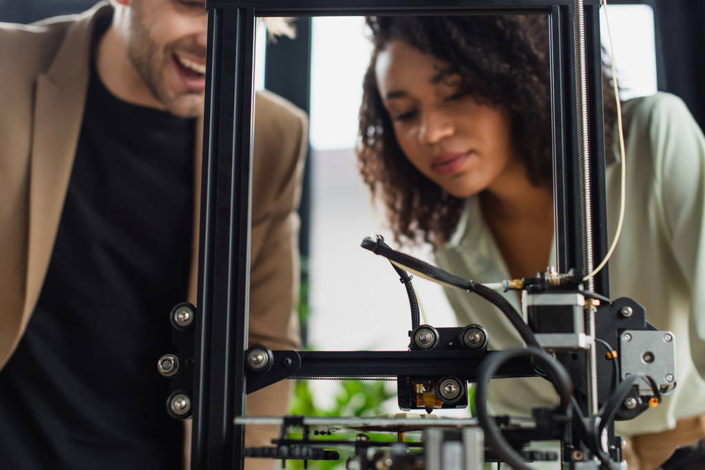 jeunes collègues interracial regardant imprimante 3D produisant figure en plastique dans le bureau moderne - Photo, image