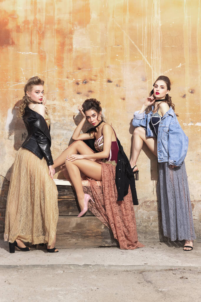 Mulheres bonitas em vestidos vintage dos anos 20. Meninas jovens em ação de arte sentado juntos e posando no fundo da parede. - Foto, Imagem