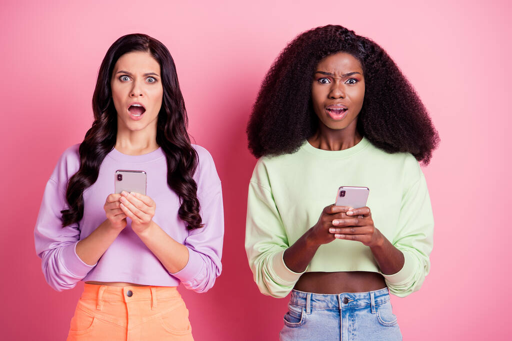 Portré vonzó őrült trendi lányok barátok barátság segítségével modul rossz visszajelzést elszigetelt rózsaszín pasztell szín háttér - Fotó, kép