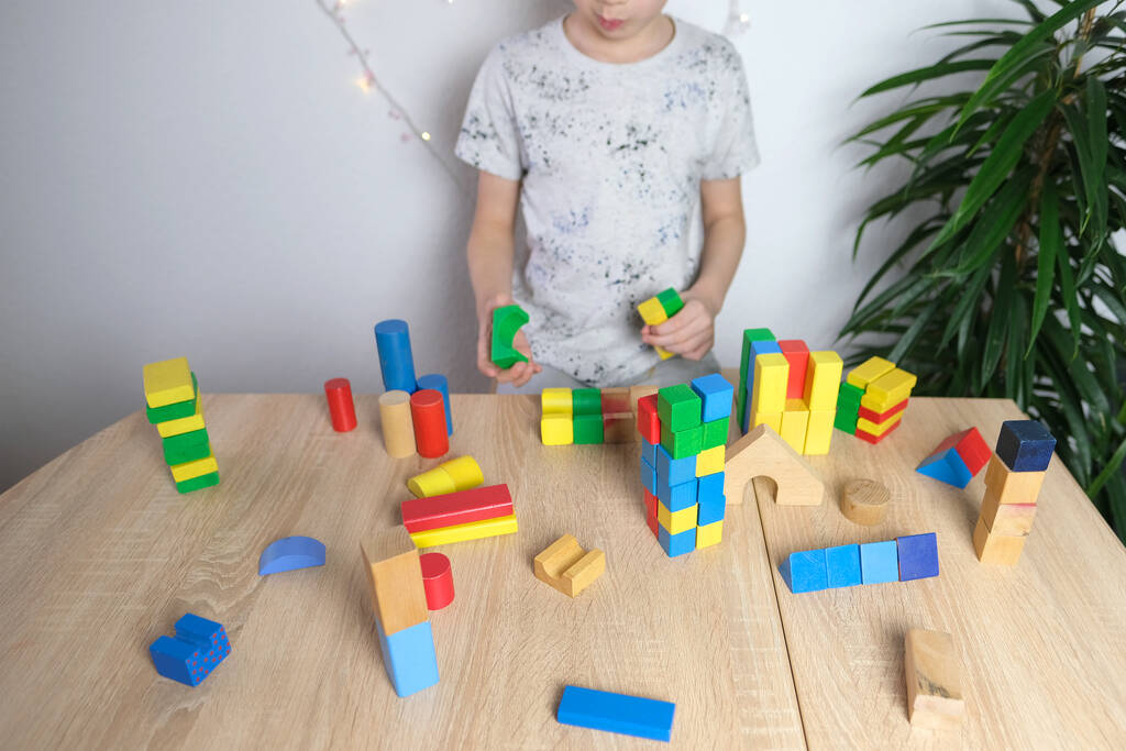 dítě, dítě si hraje s barevnými dřevěnými kostkami, staví domy a rakety, koncept rozvoje jemných motorických dovedností, hmatové pocity, kreativita, dětská zábava - Fotografie, Obrázek