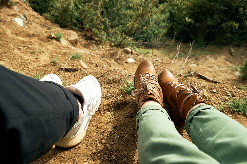 Des jambes de voyageur en couple sont assises sur une haute montagne. couple assis et faire des pieds selfie sur beau paysage avec forêt. - Photo, image