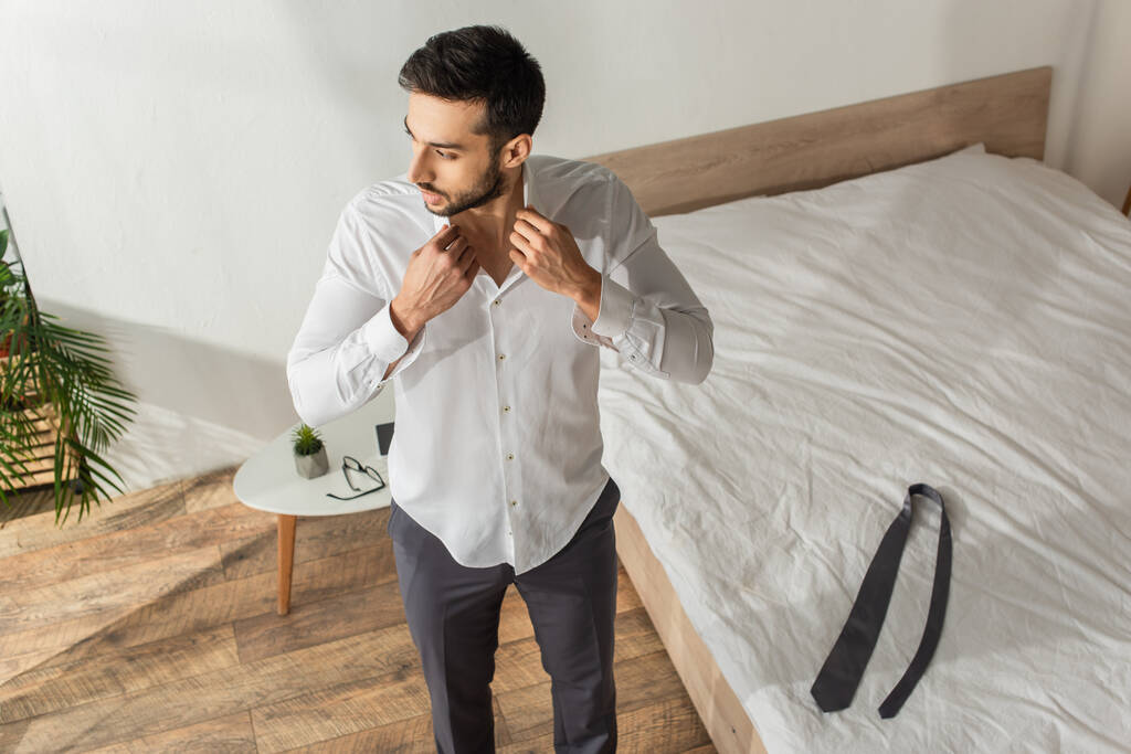 Vista aérea del hombre de negocios con camisa cerca de corbata en la cama en el dormitorio en casa  - Foto, imagen